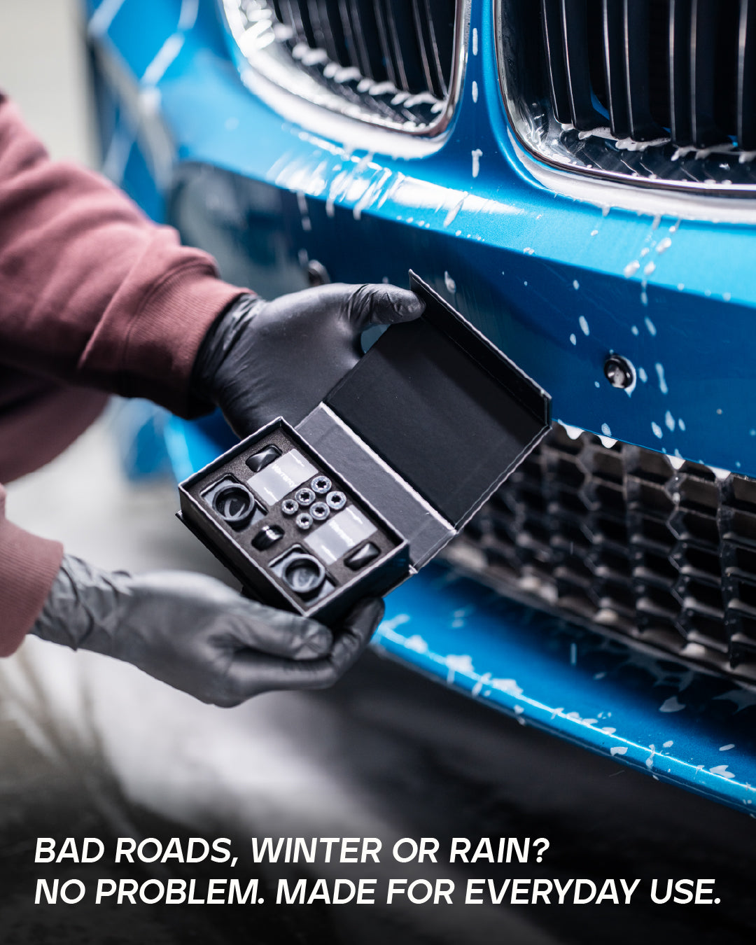 QuickPlate kit contents displayed in front of a blue BMW bumper showing all included hardware